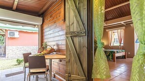 Interior de madera con una mesa de comedor y sillas, una puerta corredera y vistas al exterior.