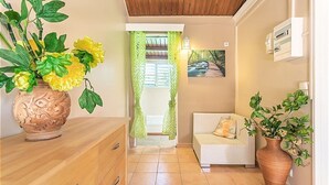 Una habitación con techo de madera, un sofá blanco con cojín, un aparador de madera y un jarrón grande con flores amarillas.