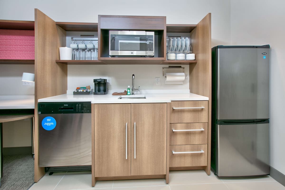 A compact kitchen with a microwave, refrigerator, dishwasher, and a coffee maker.