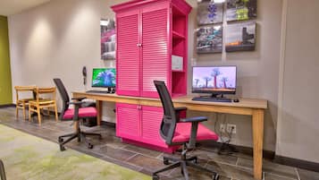 A room with two desks, each with a computer monitor, a keyboard, and a chair. There is a large pink cabinet in the center.