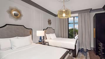 A hotel room with two beds, a chandelier, a large mirror, and a view of the outdoors.