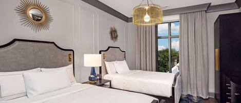 A hotel room with two beds, a chandelier, a large mirror, and a view of the outdoors.