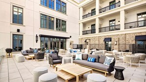 A spacious outdoor seating area with multiple sofas and chairs, a wooden coffee table, and round ottomans.