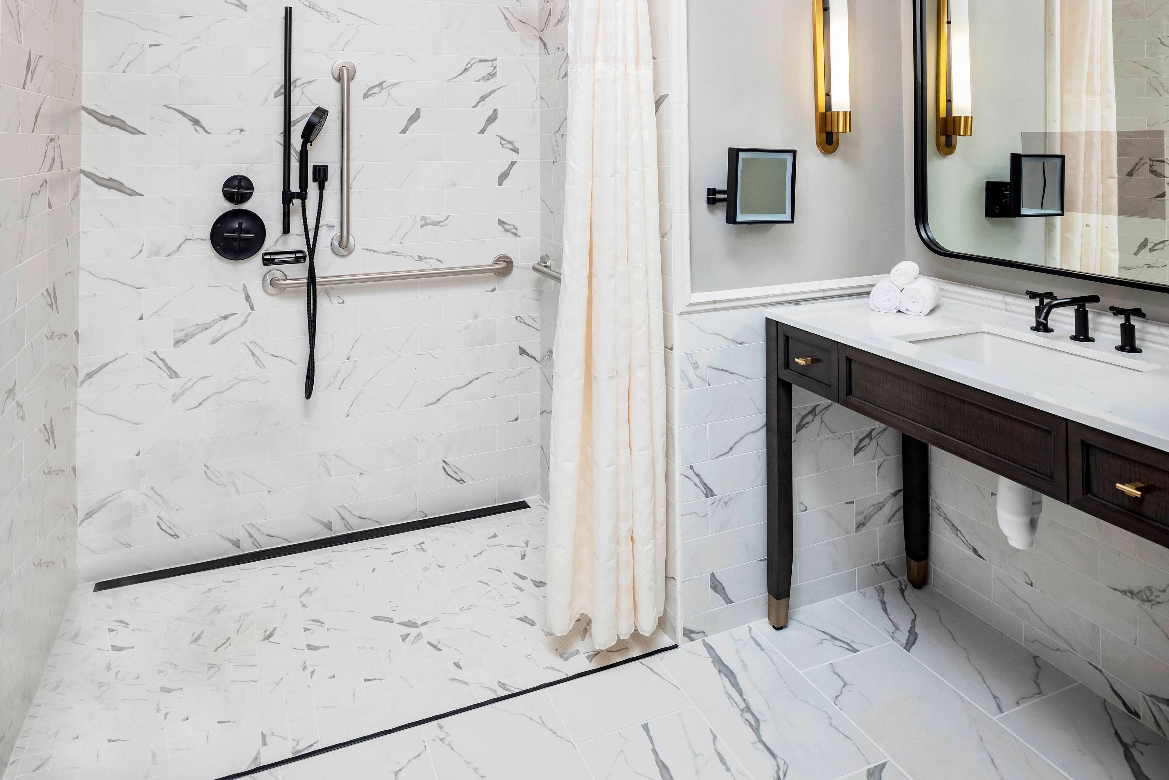 A modern bathroom with a shower area, a vanity with a sink, and a large mirror.