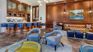 A spacious lobby with a bar area, seating arrangements, and a large painting on the wall.