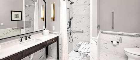 A modern bathroom with a large mirror, a sink with a dark countertop, a shower with a glass door, and a toilet with a grab bar.