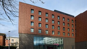 A modern building with a brick facade, multiple windows, and a large glass entrance.