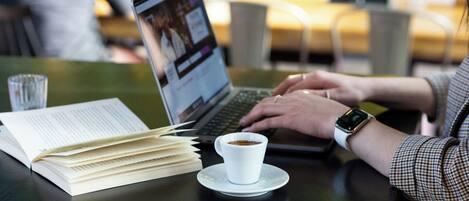 A person working on a laptop with a cup of coffee on a table.