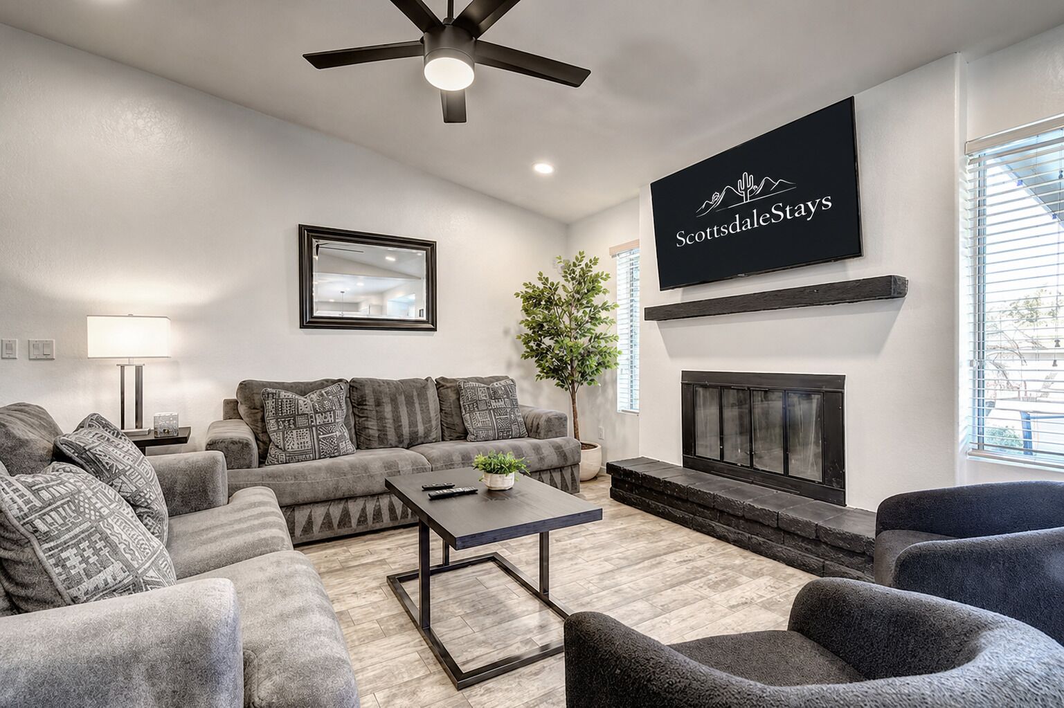 A modern living room with a grey sofa set, a coffee table, a fireplace, and a mounted TV.