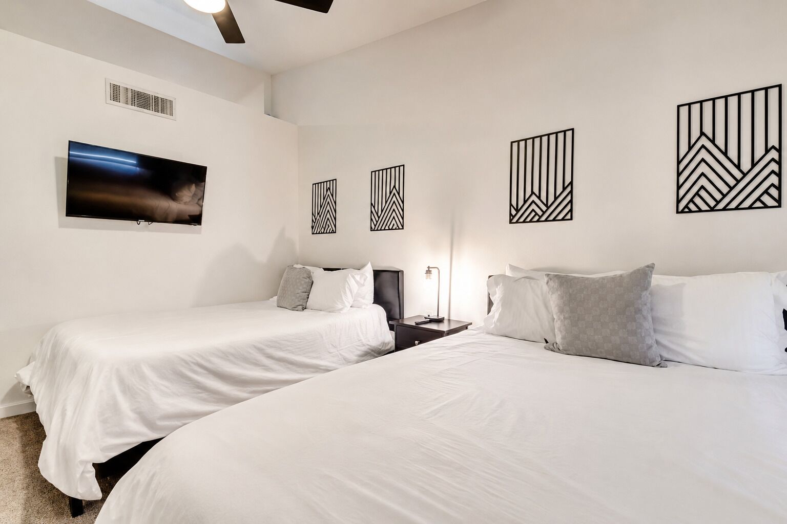 Una habitación de hotel con dos camas, un televisor de pantalla plana y decoración mural.