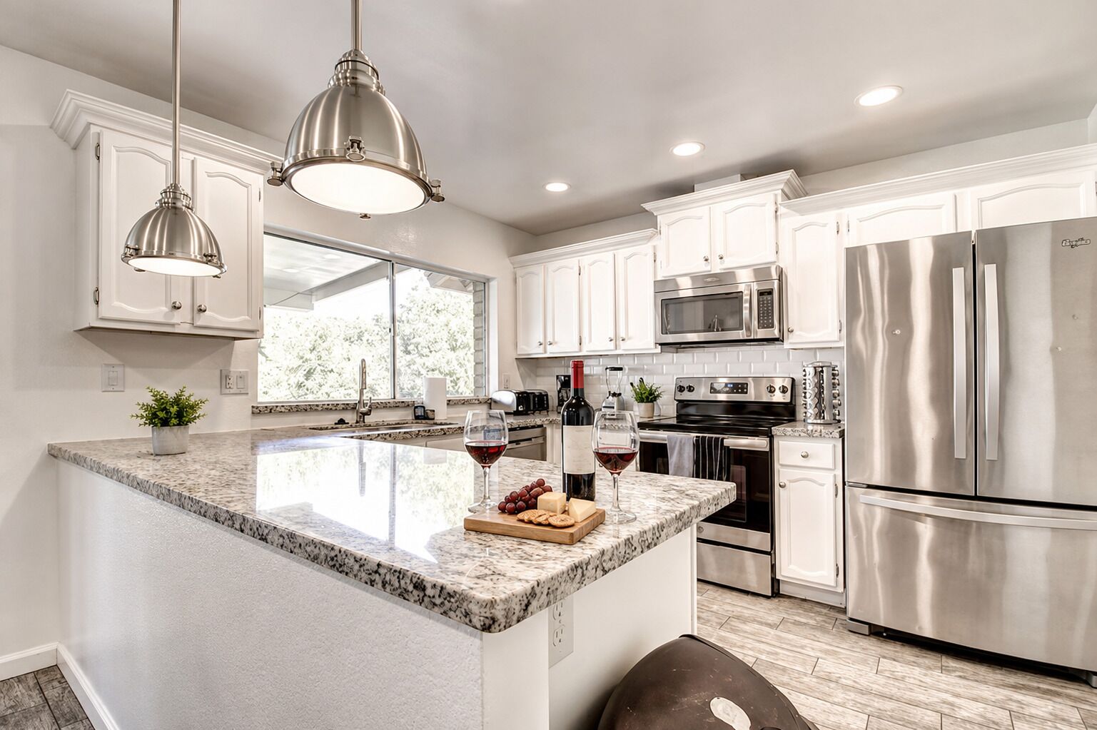 A modern kitchen with a central island, stainless steel appliances, and pendant lighting.