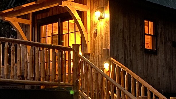 Een houten chalet met een balkon en een trap naar de ingang.