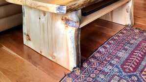 Een gezellige woonkamer met een houten salontafel, een bank met decoratieve kussens, een lamp en een keuken met kasten en een koelkast.