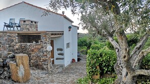 A rustic stone building with a white exterior, a stone wall, and a cobblestone path leading to a wooden door.