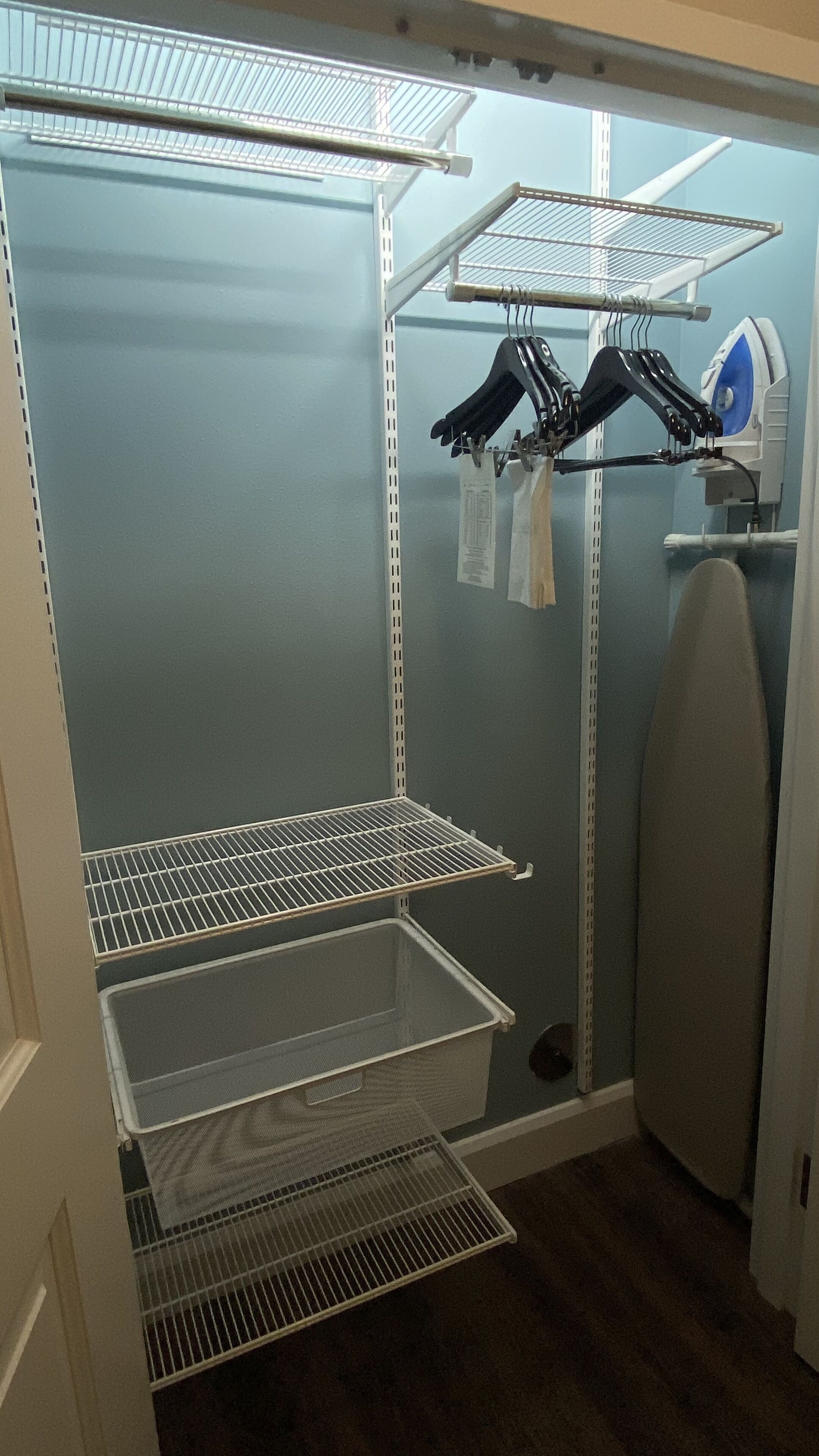 A walk-in closet with metal shelving, a drying rack, and a large mirror.