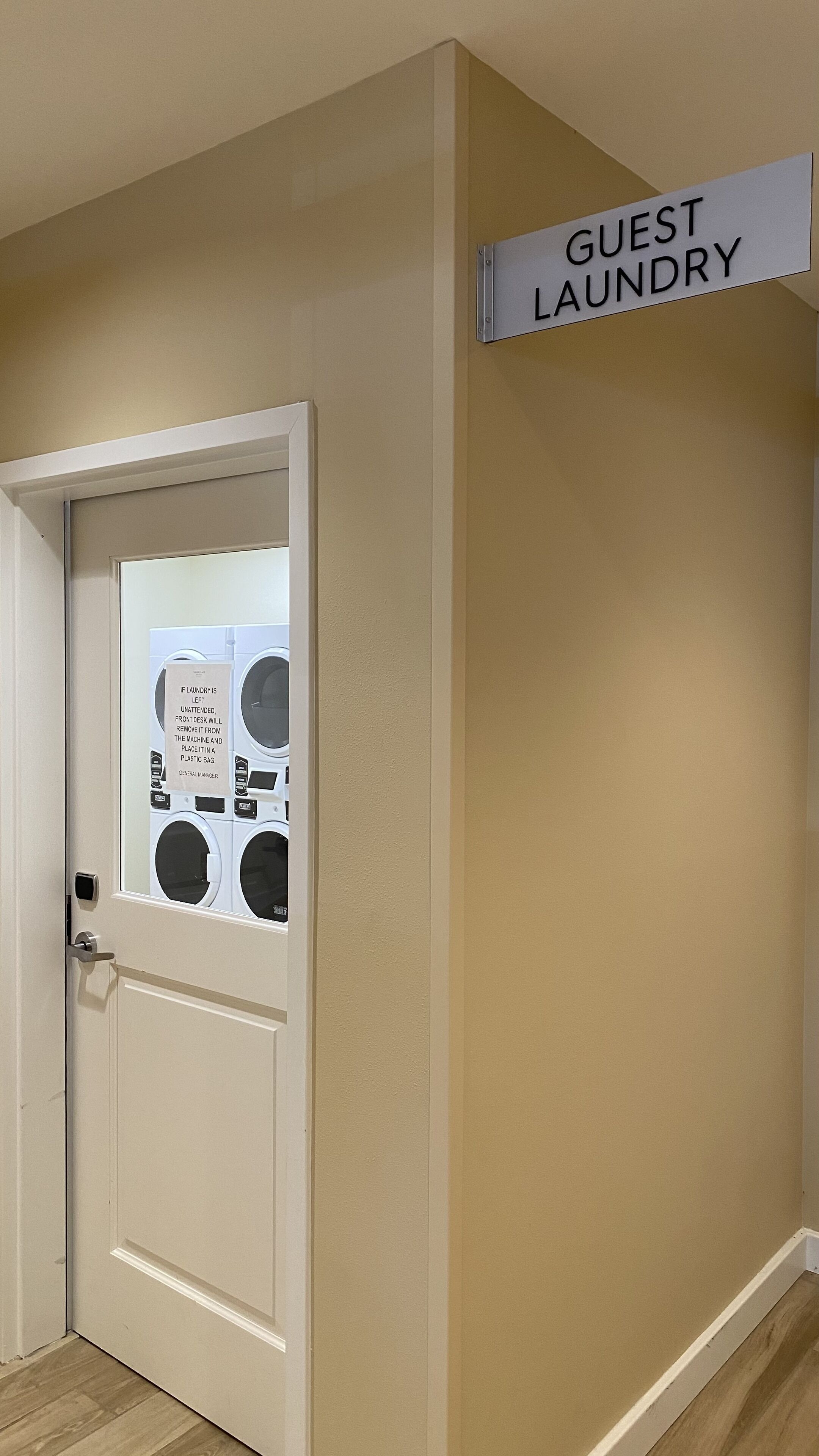 Una puerta con un letrero que dice "GUEST LAUNDRY" y un aviso sobre ropa que queda sin atender.