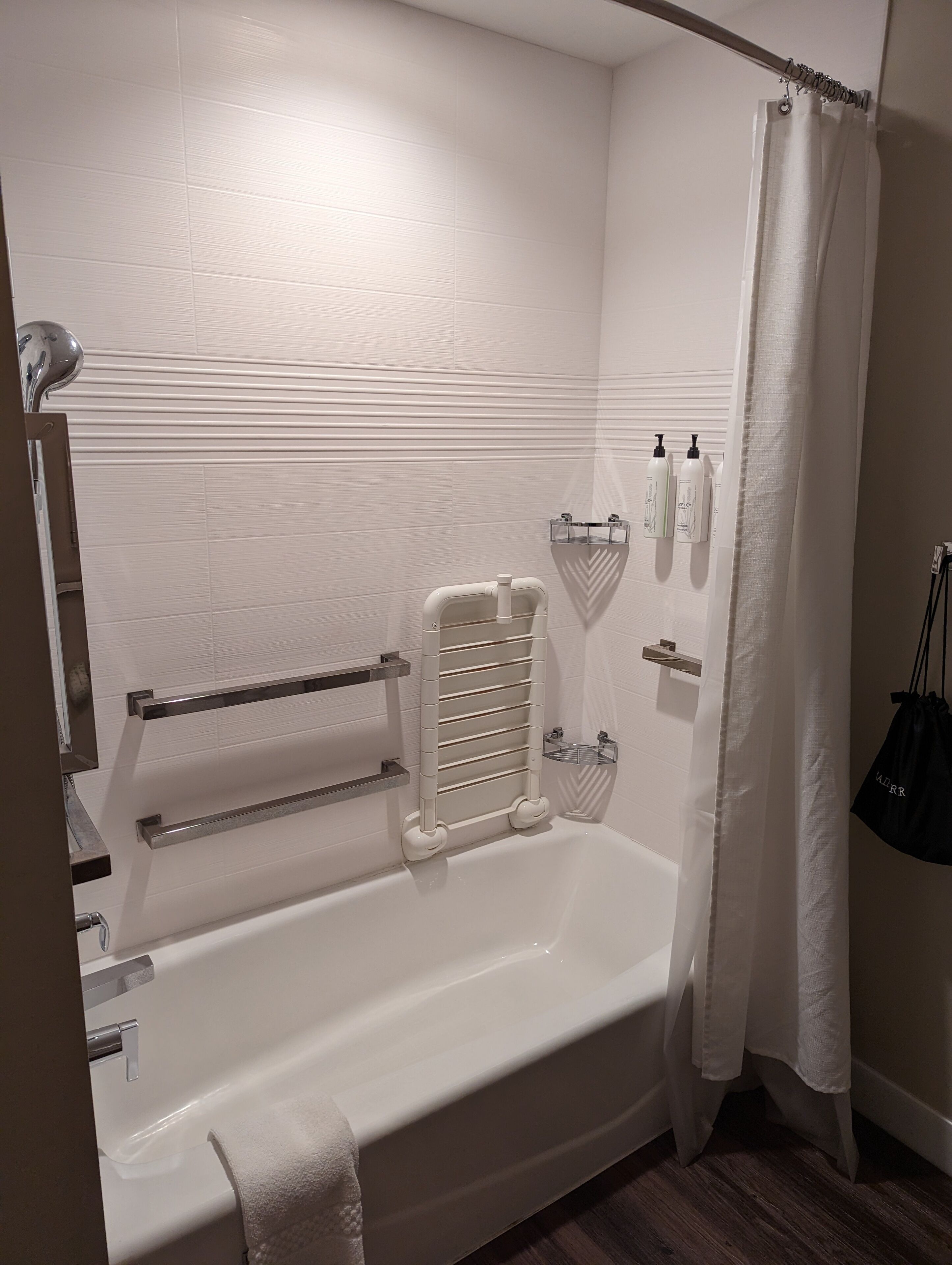 A modern bathroom with a bathtub, towel rack, and shower curtain.