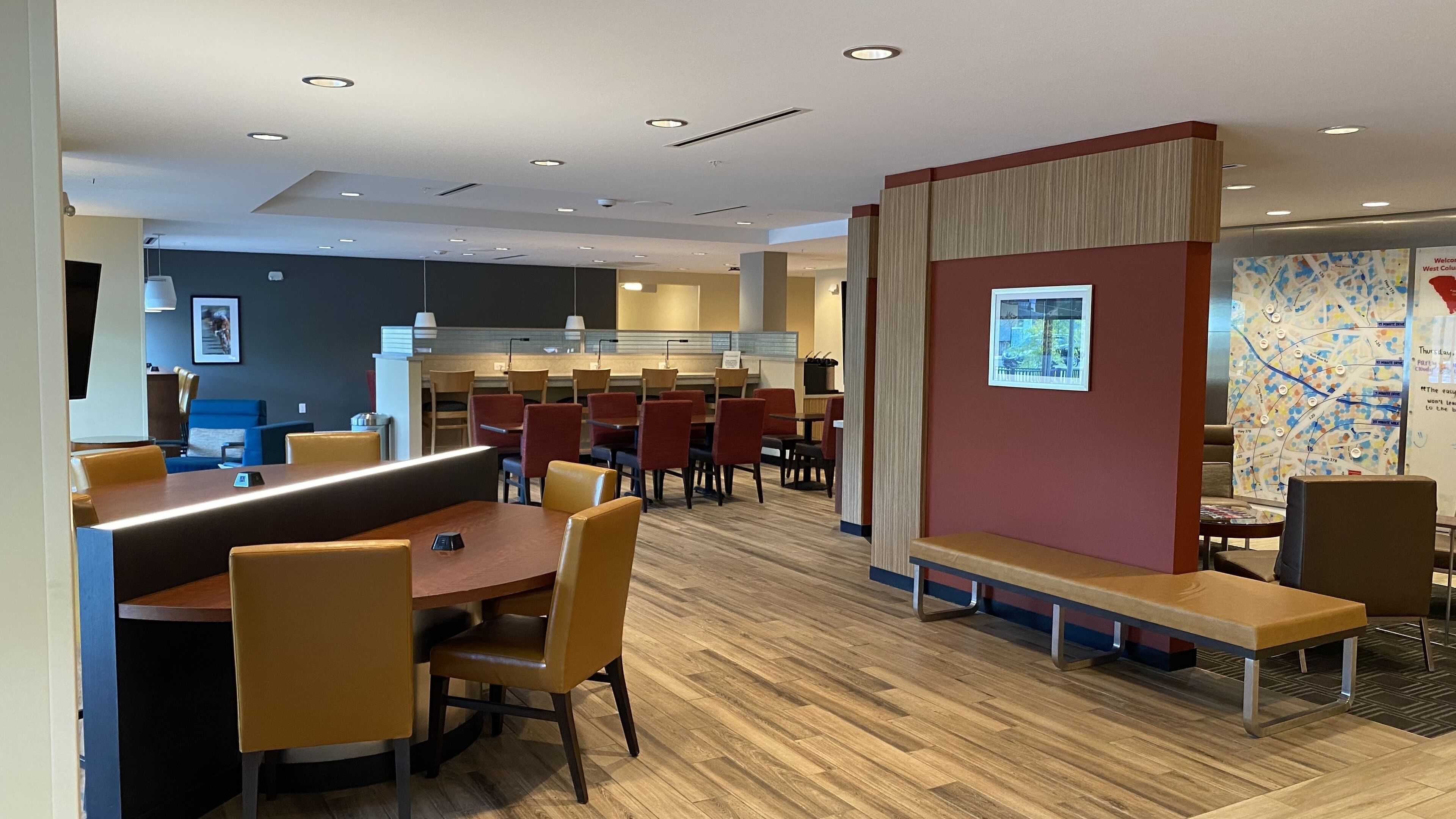 A modern dining area with booths and tables, a kitchen in the background, and a map on the wall.