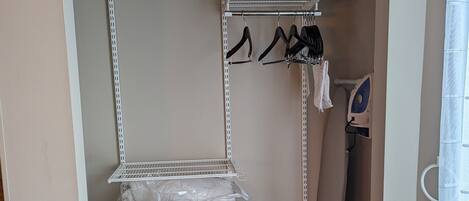 Un vestidor con estantes de metal, bolsas de plástico y una barra para colgar.