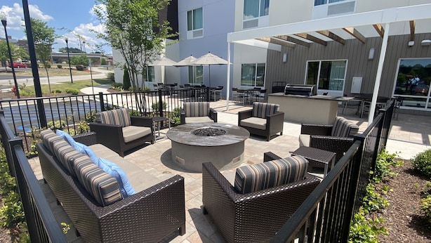 An outdoor patio area with wicker furniture, a circular fire pit, and umbrellas. - TownePlace Suites Columbia West/Lexington (West Columbia)