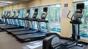 A row of treadmills in a gym with large windows and a sign about safety rules. - TownePlace Suites Columbia West/Lexington (West Columbia)