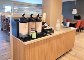 Uma estação de café com vários dispensadores e uma caneca.
