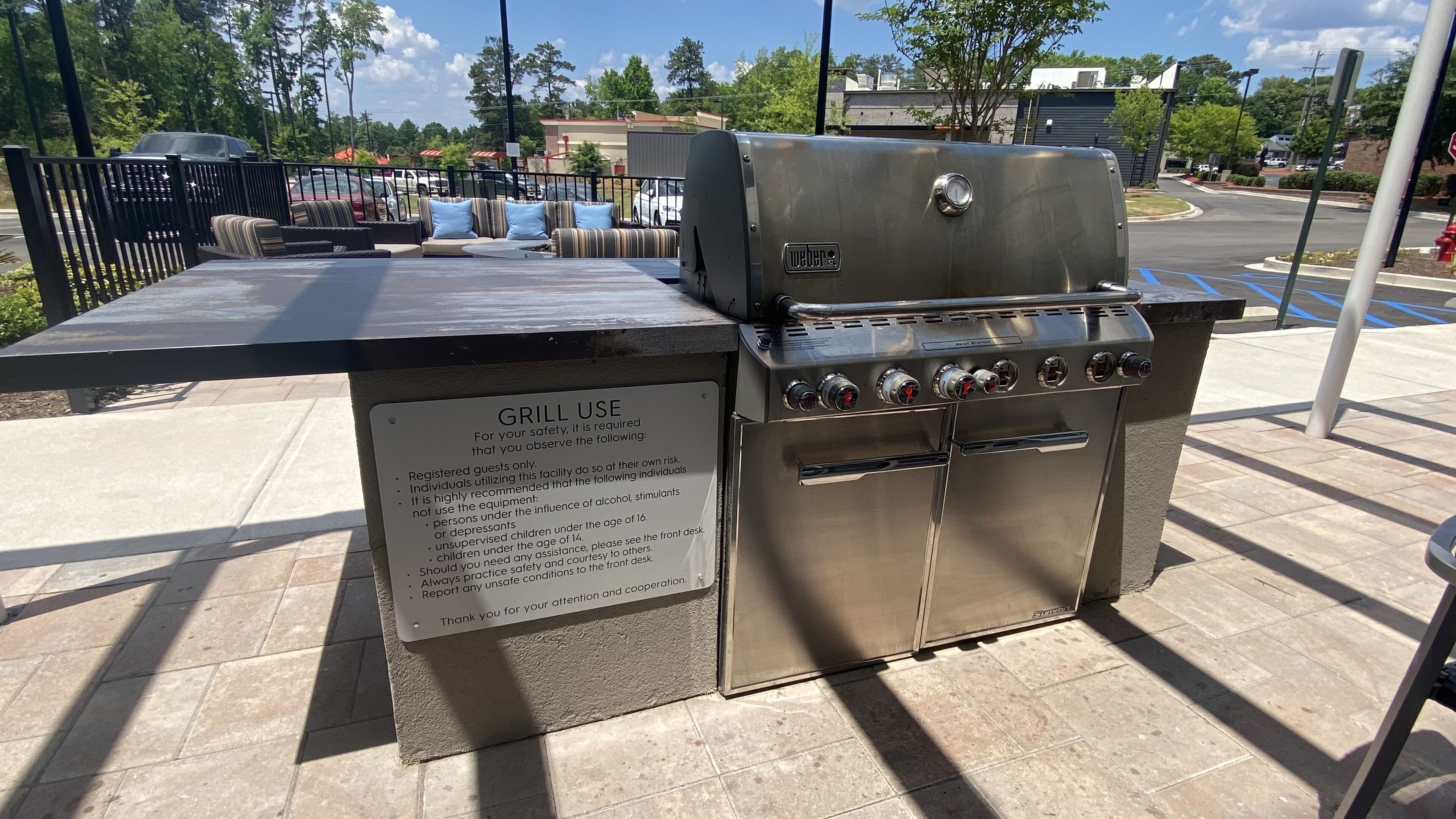 Een buitenbarbecue met een bord waarop veiligheidsvoorschriften staan.