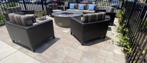 An outdoor patio with wicker furniture, a round table, and a fire pit.