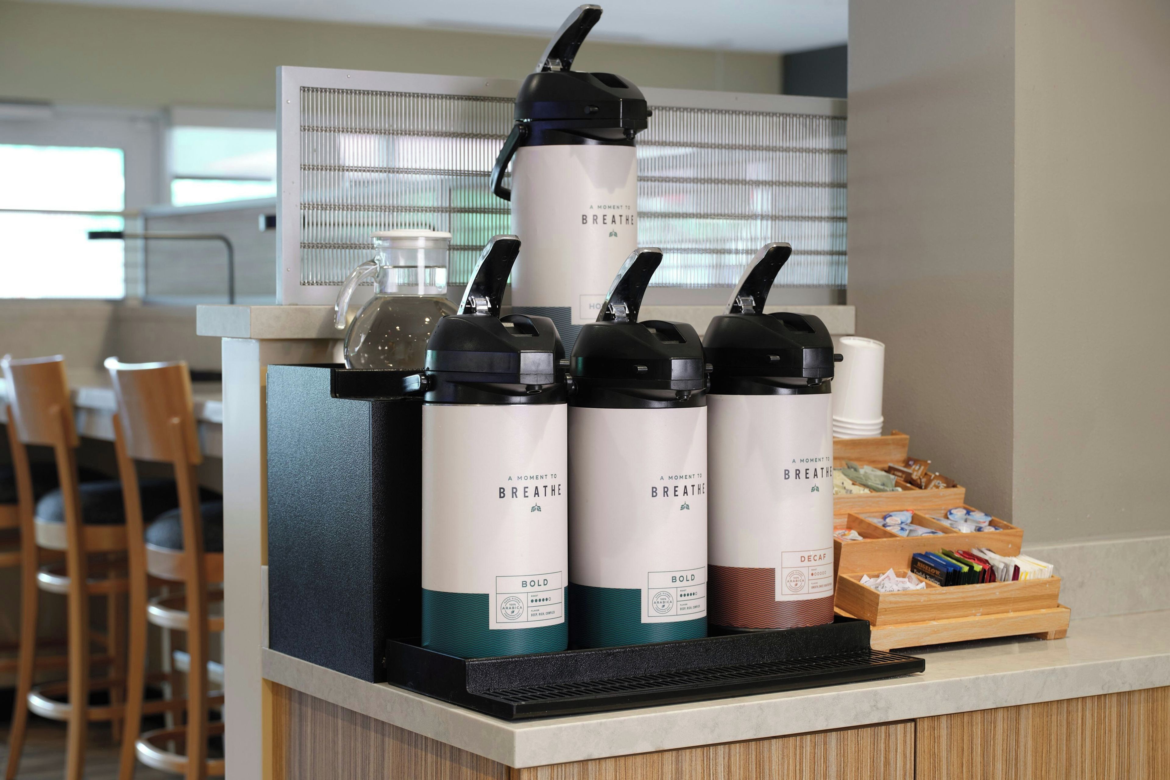 A coffee station with multiple coffee dispensers and a tray of coffee pods.