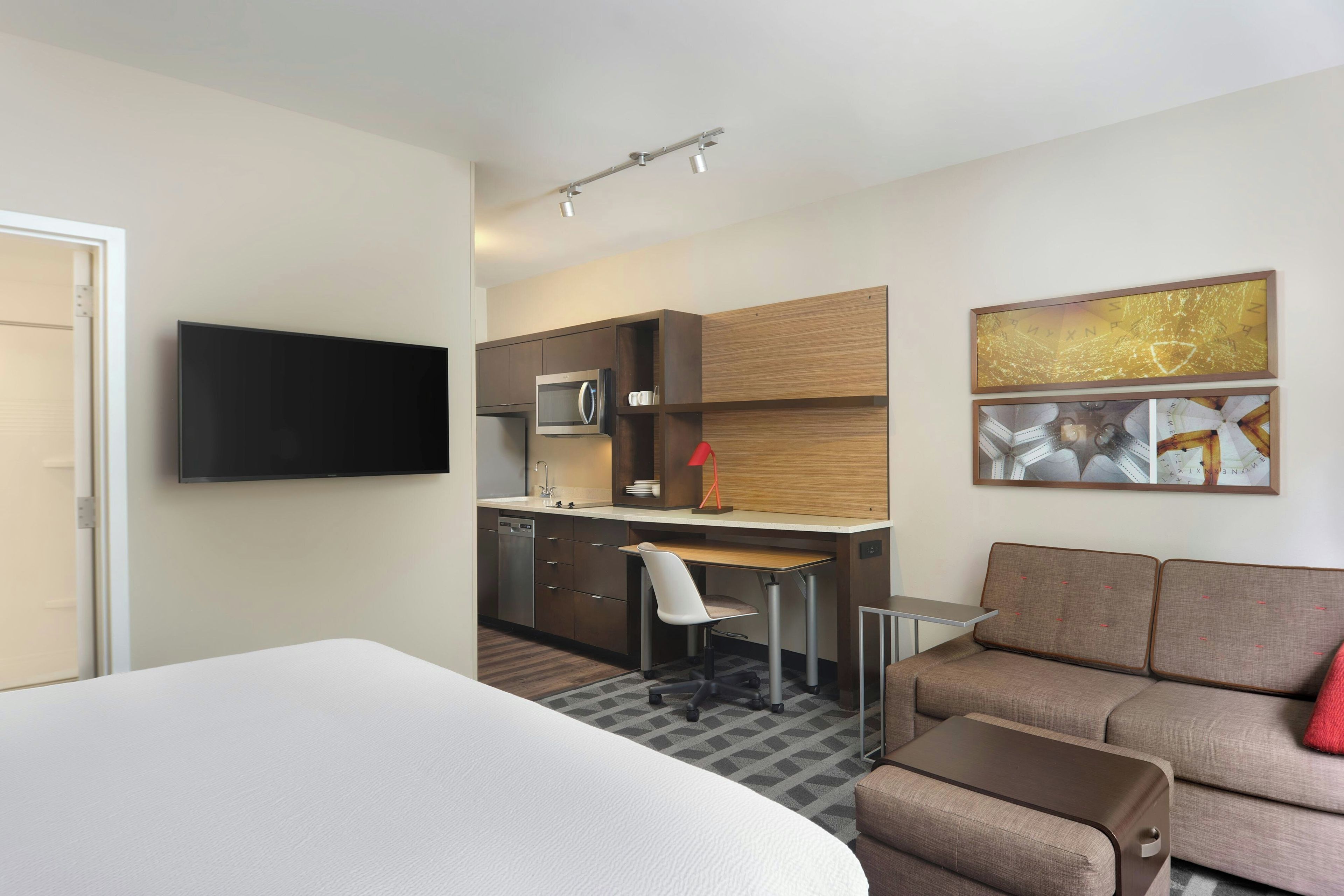 Une chambre d’hôtel moderne équipée d’un lit, d’une kitchenette, d’un coin salon et d’œuvres d’art accrochées au mur.