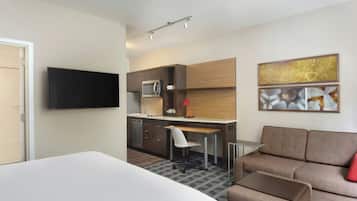 Une chambre d’hôtel moderne équipée d’un lit, d’une kitchenette, d’un coin salon et d’œuvres d’art accrochées au mur.