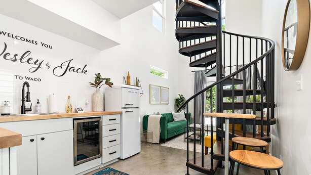 Eine moderne Küche mit Backofen, einem weißen Kühlschrank und einer schwarzen Wendeltreppe.