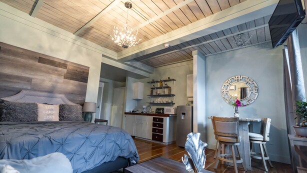Un dormitorio con una cama grande, un comedor con mesa y sillas, una zona de cocina y un espejo decorativo en la pared.
