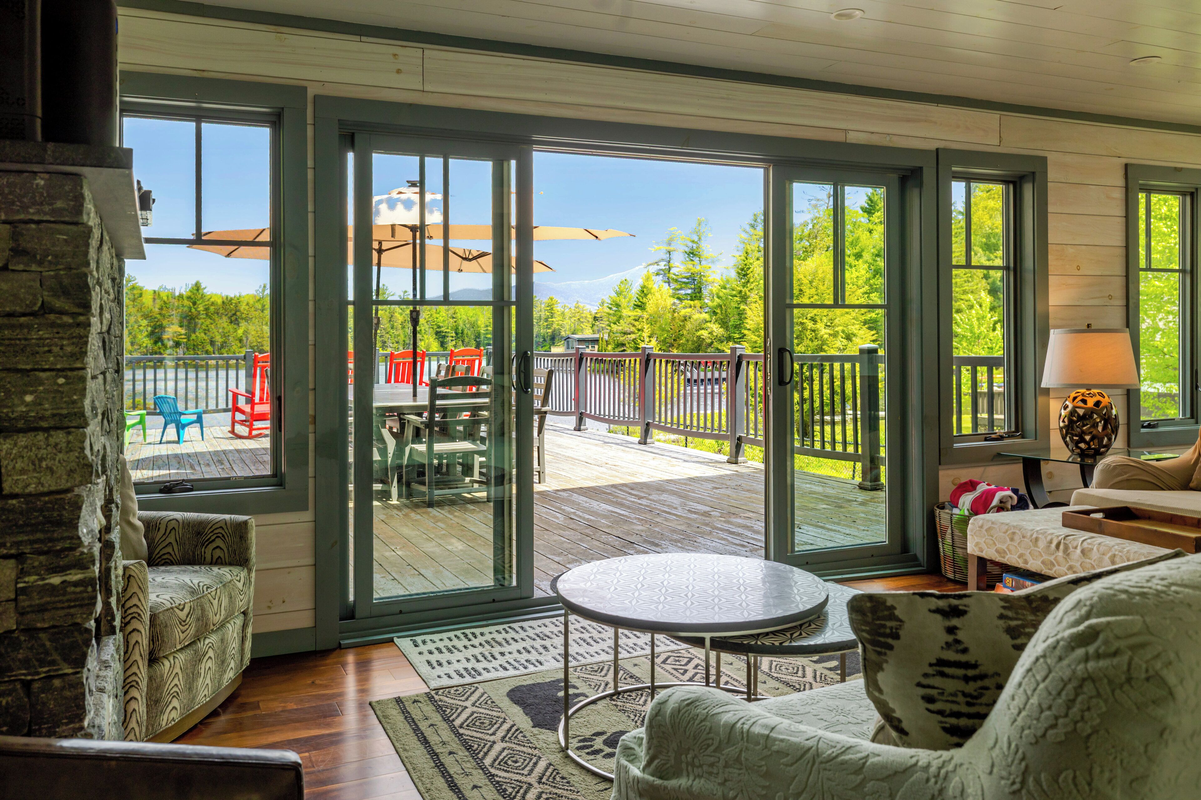 A room with a view of a deck, outdoor furniture, and a stone wall.