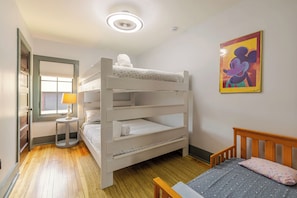 Ein Schlafzimmer mit Etagenbetten, einem Fenster, einer Lampe und einem Mickey-Mouse-Bild.