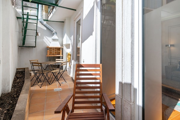 A patio area with a wooden chair, a small table, and a brick bench. - Great Location & Family Apartment (Lisbon)