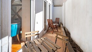 A narrow outdoor patio with wooden benches and a table, a blue chair, and a door leading to an interior space. - Great Location & Family Apartment (Lisbon)