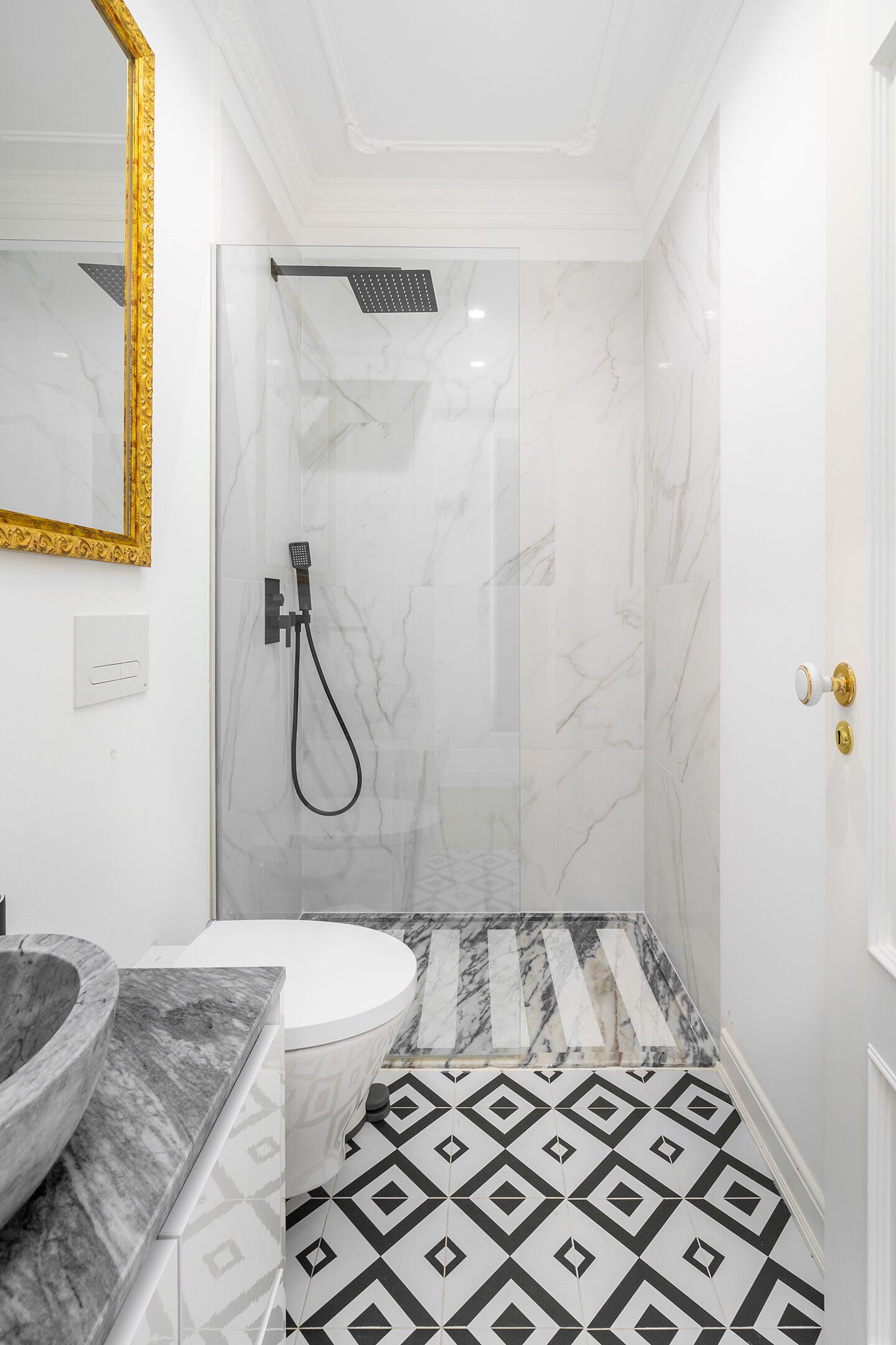 Un baño con ducha de mármol, lavabo con recipiente de mármol y retrete.