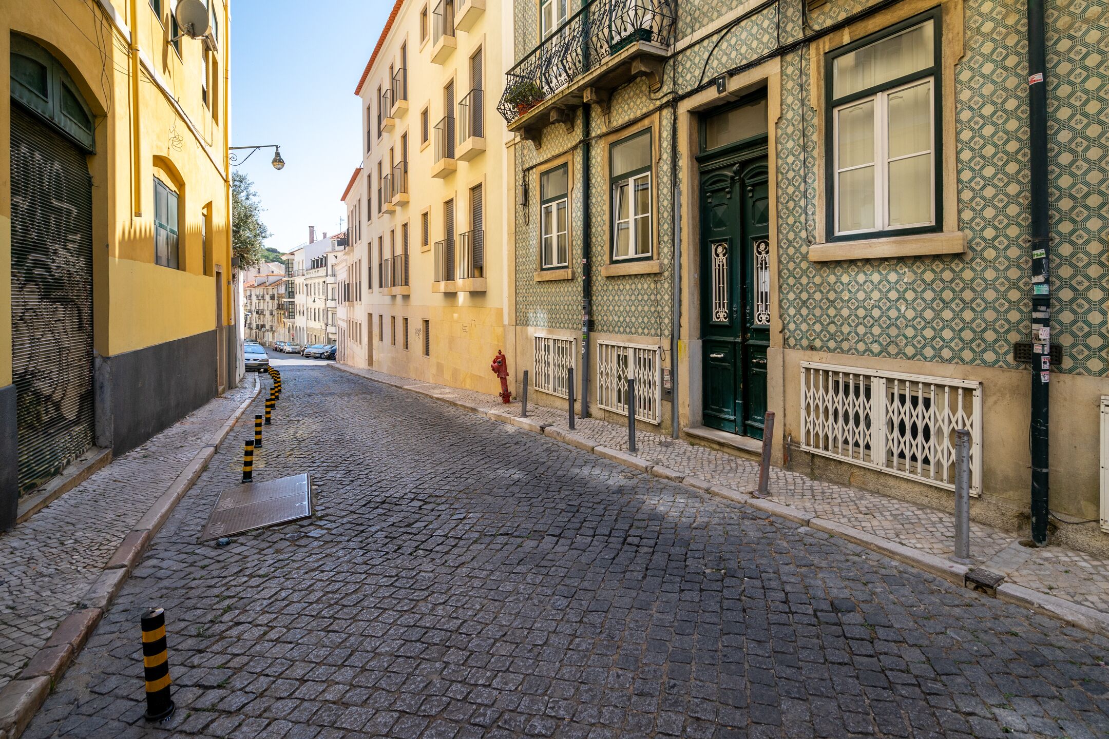 A cobblestone street lined with historic buildings, featuring balconies and patterned facades.