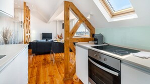 A modern kitchen with wooden beams, a dining area, and a view through a skylight. - Premium River View Apartment (Lisbon)
