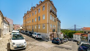 A street with parked cars and a building with multiple windows and balconies. - Premium River View Apartment (Lisbon)