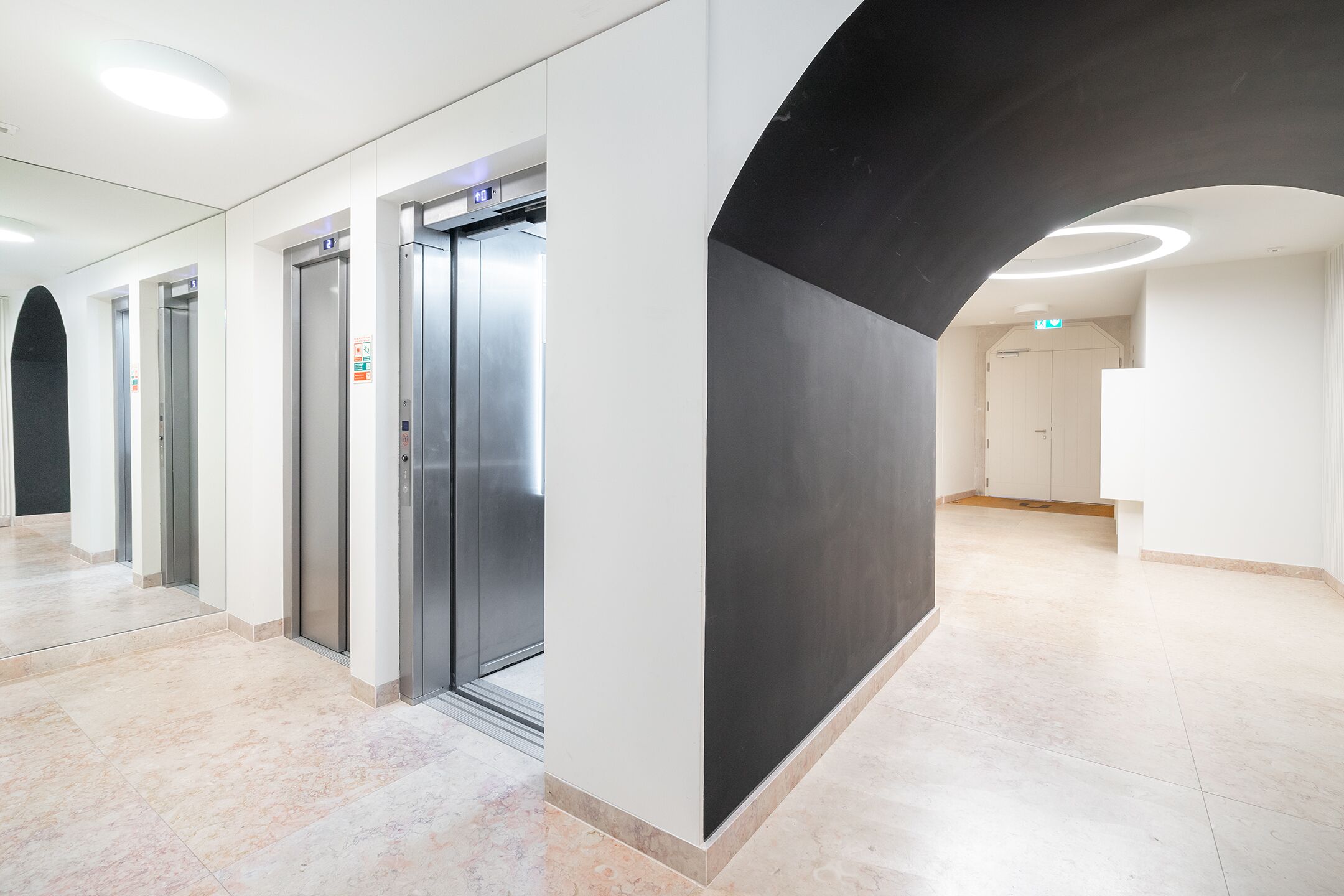 A modern hallway with elevators and a black accent wall.