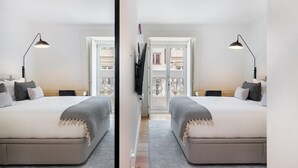 Une vue en miroir d’une chambre à coucher avec deux lits, un téléviseur et un balcon donnant sur des immeubles.