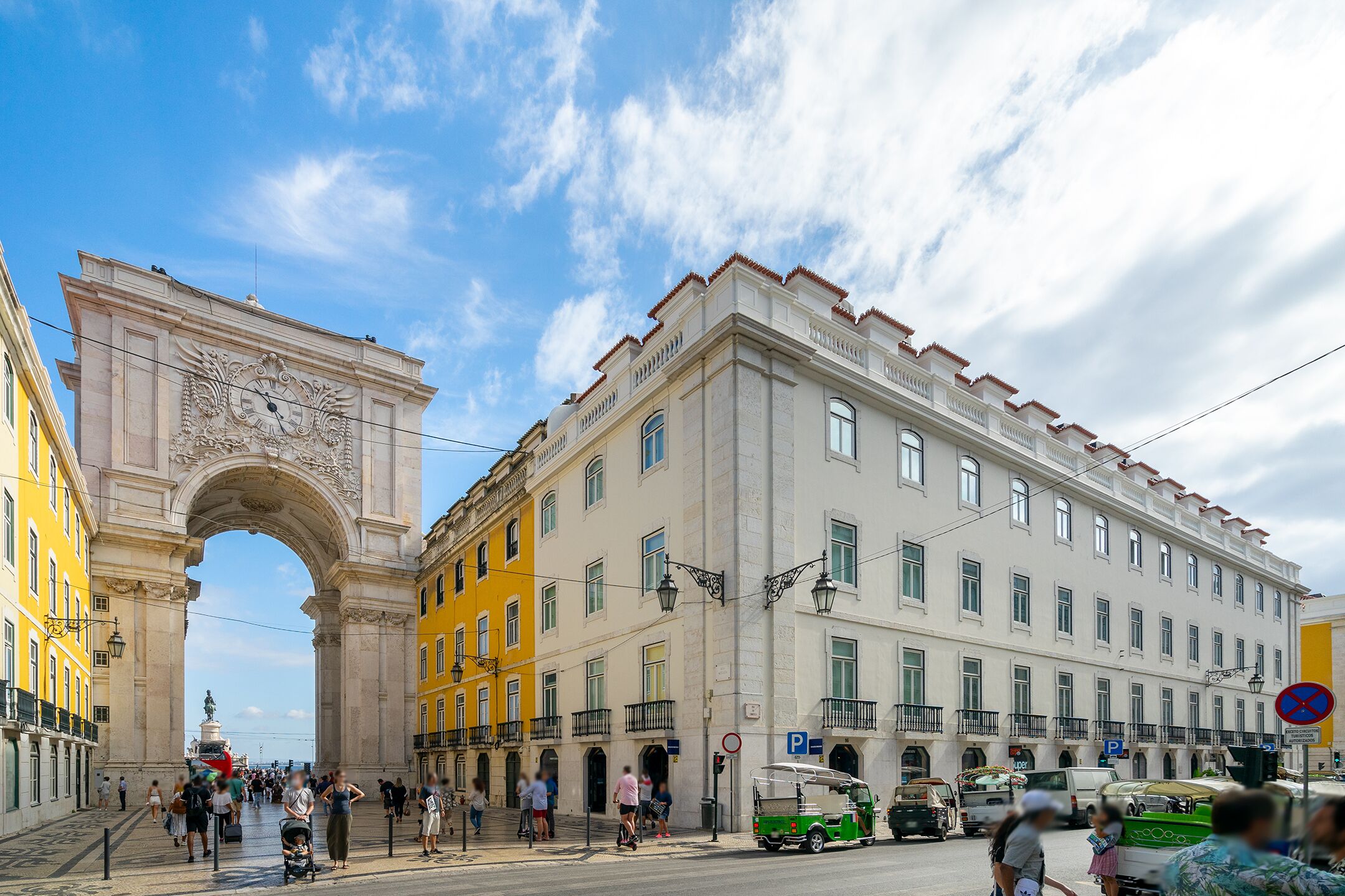 A historic building with an ornate archway, a large white facade, and multiple windows.