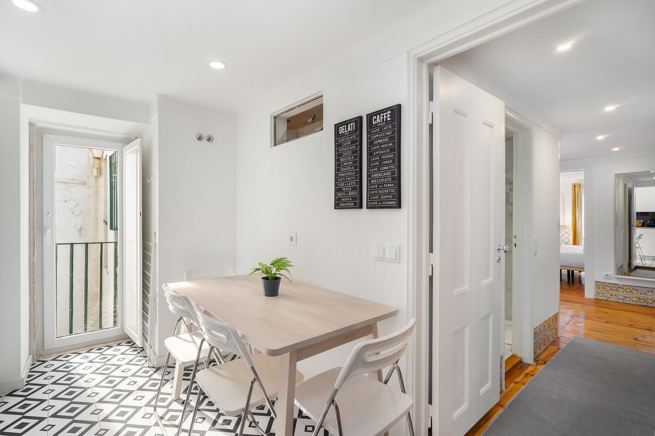 Un área de comedor con una mesa y sillas, una planta en maceta y dos carteles negros con texto blanco.