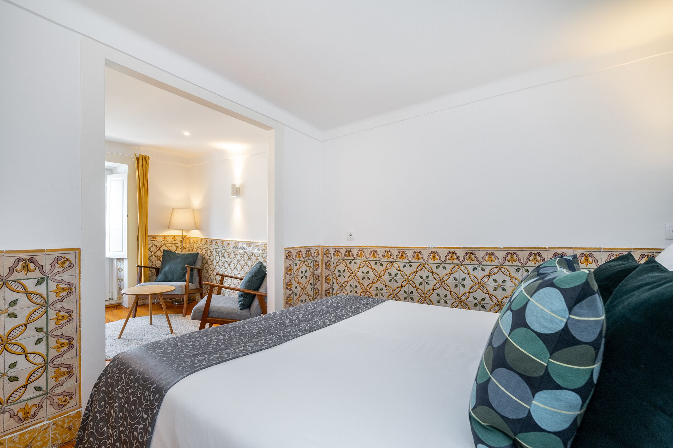 A hotel room with a bed, a chair, a lamp, and a decorative wall panel.
