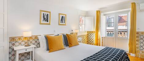 Habitació d'hotel amb llit, una tauleta de nit, finestra amb cortines i vista al balcó.
