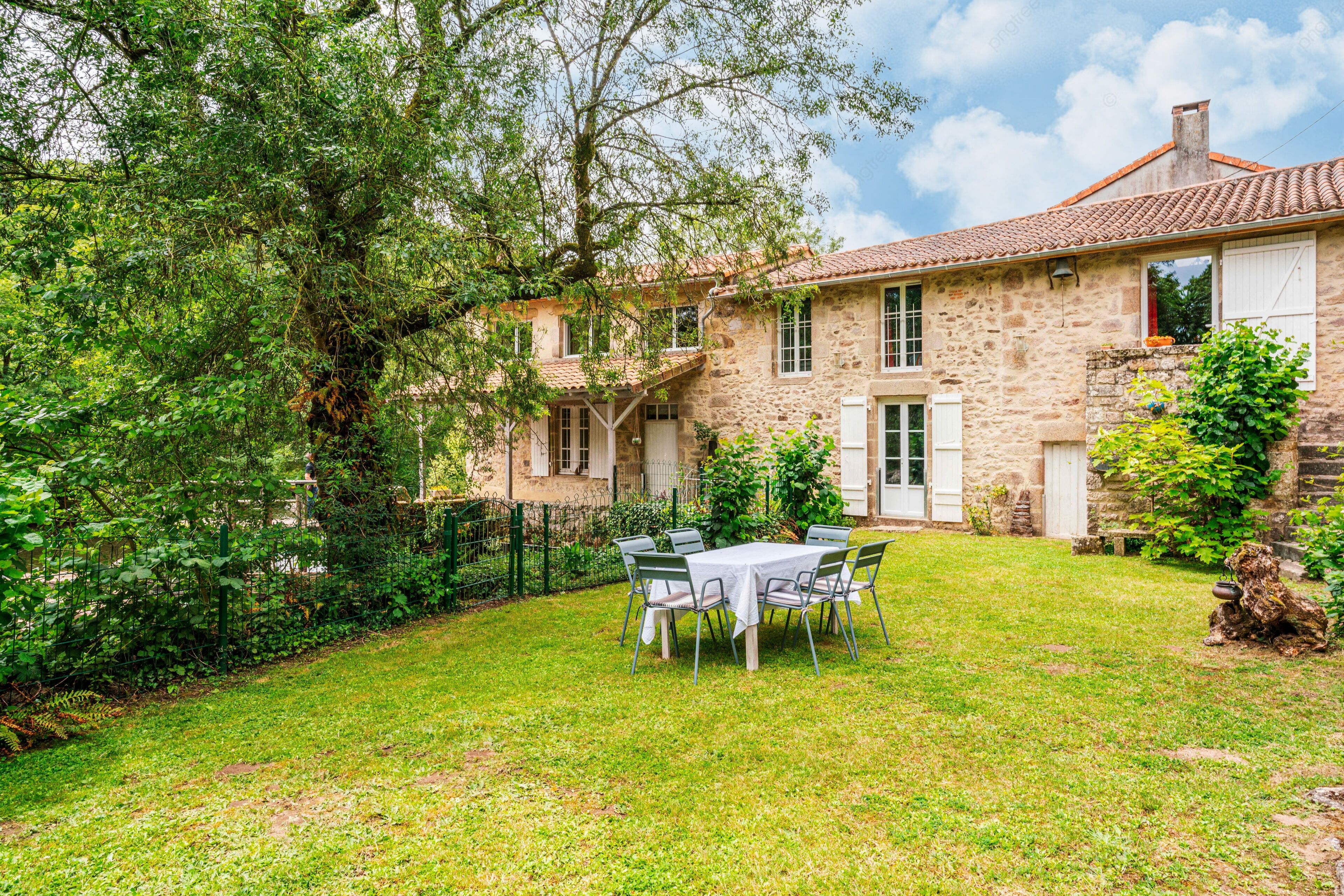 A stone house with a garden and a table set for dining.