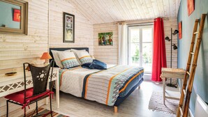 A wooden-paneled bedroom with a bed, a chair, a table, and a window with curtains. - Le Moulin de Pilet 4* - Proche Puy du Fou (Mortagne-sur-Sèvre)