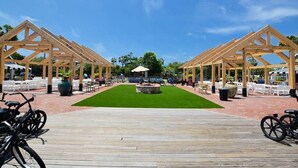 A wooden deck with a central lawn and two wooden pergolas on either side.